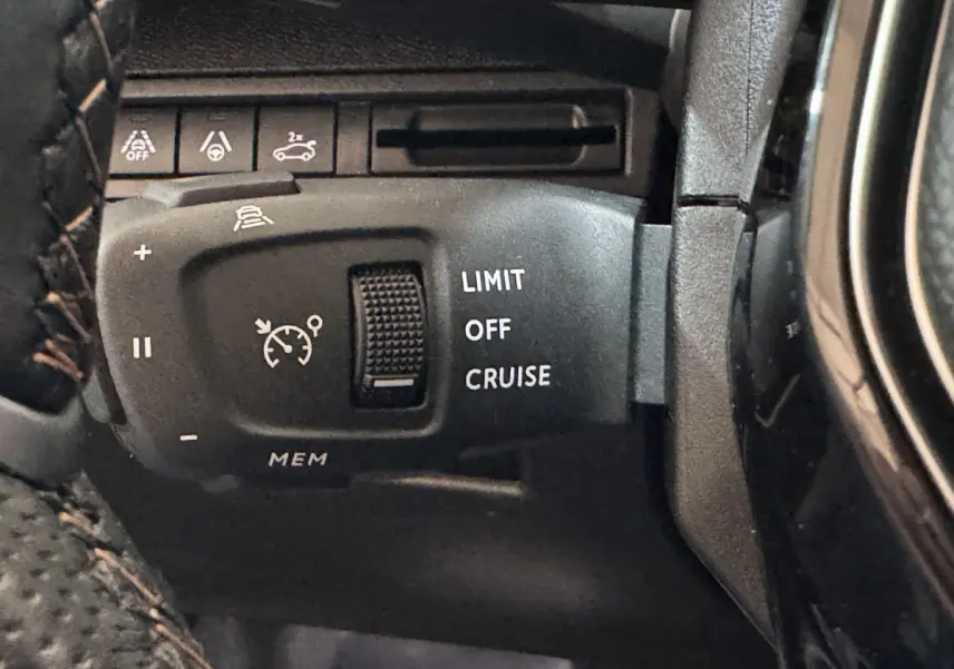Gros plan sur la commande de régulateur de vitesse et limiteur, intérieur noir du Peugeot 3008 gris clair.