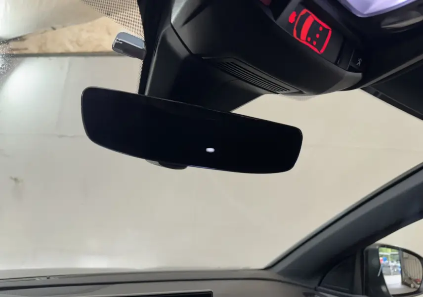 Vue intérieure du rétroviseur central noir et du plafonnier avec témoin rouge dans un Peugeot 3008 gris clair.