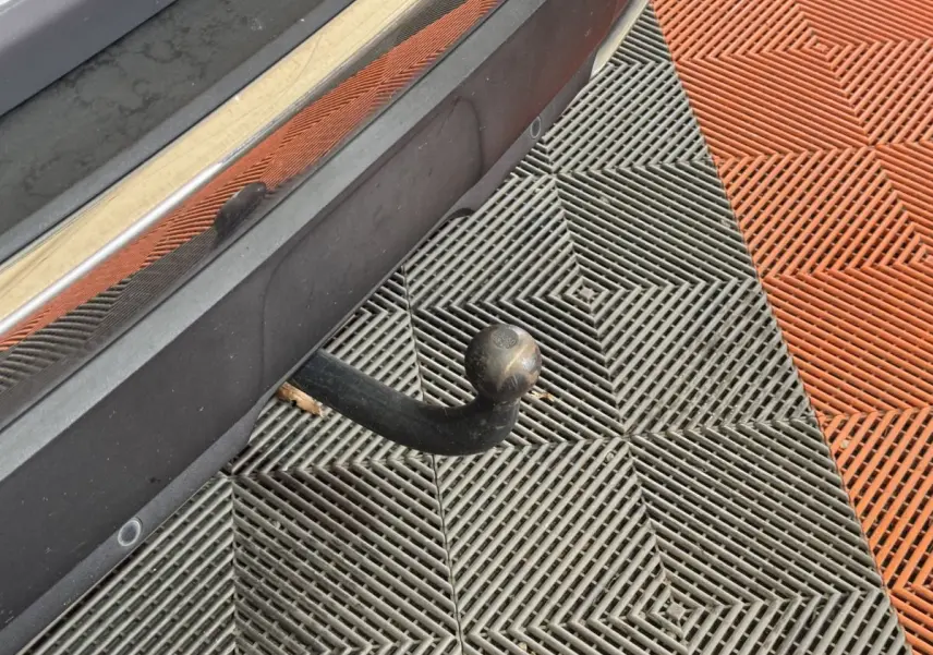 Gros plan sur l'attelage de remorque arrière d'un Peugeot 3008 gris clair, avec capteurs de stationnement visibles.