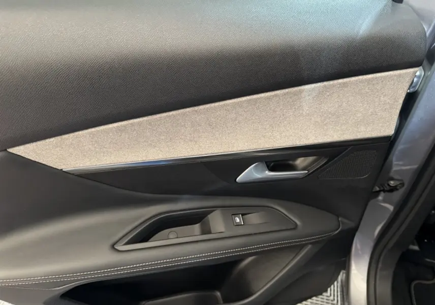 Vue rapprochée de la porte côté gauche gris clair du Peugeot 3008 2021 avec garniture noire et beige et commande de vitre.
