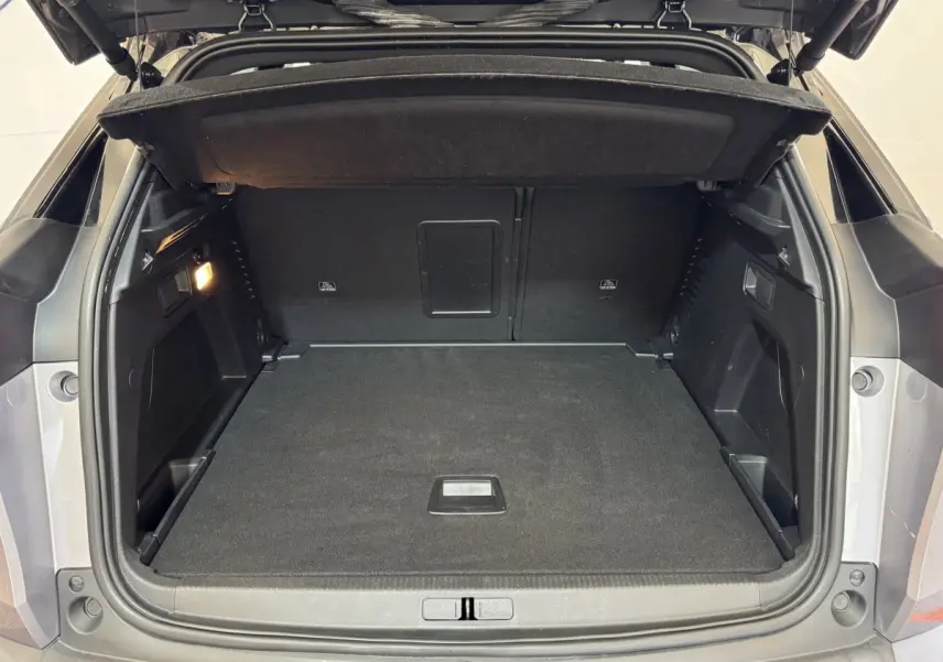 Coffre ouvert vu de l'arrière d'un Peugeot 3008 gris clair, montrant un espace de chargement propre et spacieux.