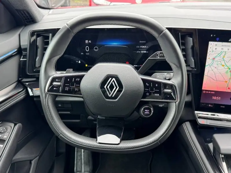 Vue rapprochée du volant multifonction noir avec logo Renault, tableau de bord digital et écran tactile du Renault Austral 2024.