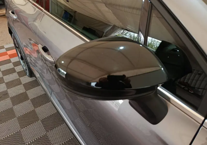 Rétroviseur noir brillant en gros plan sur le côté gauche d'une Renault SYMBIOZ gris métallisé, vue partielle latérale.