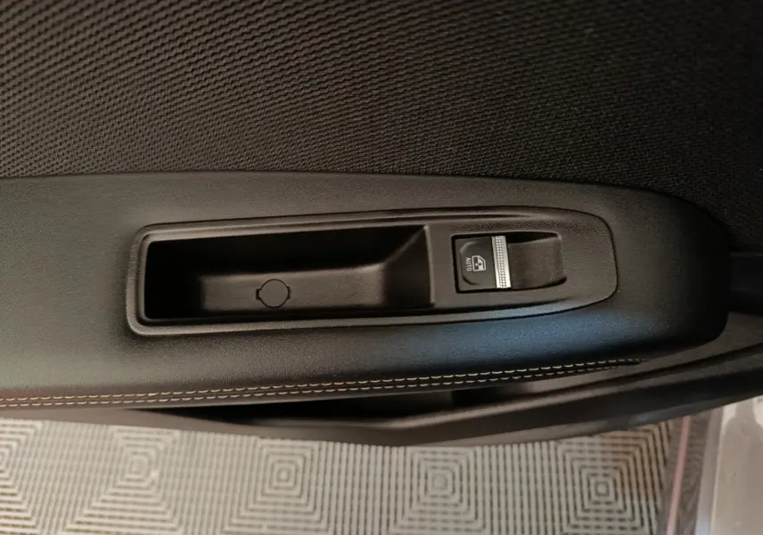 Gros plan sur la commande de lève-vitre côté porte intérieure d'une Renault SYMBIOZ 2025, finition noire avec surpiqûres.