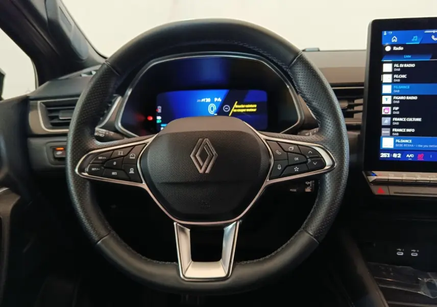 Vue frontale du volant noir perforé de la Renault SYMBIOZ 2025 avec tableau de bord numérique et écran tactile latéral.