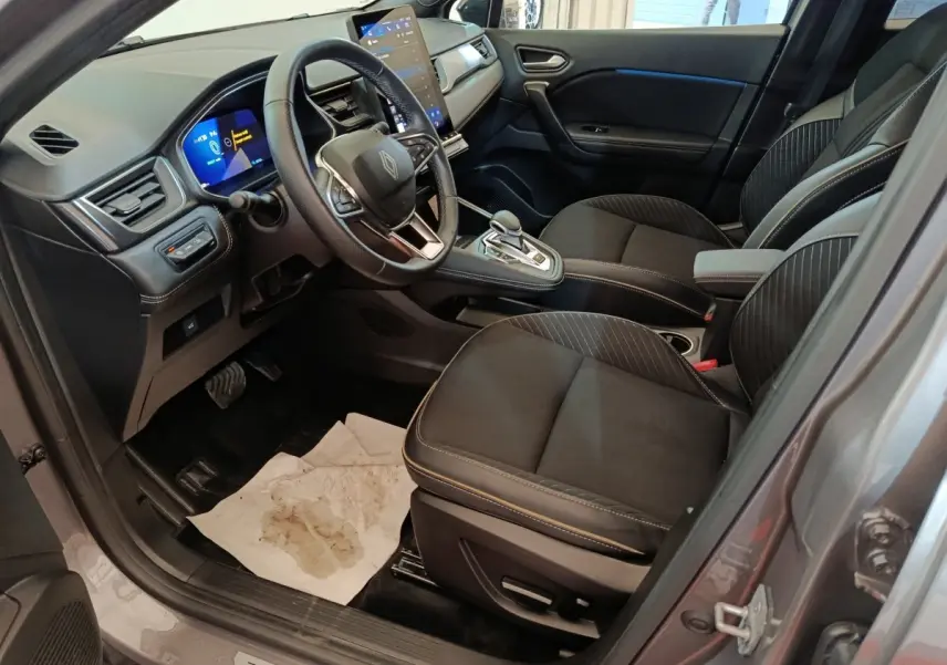 Vue intérieure côté conducteur du Renault Symbioz 2025, sièges noirs et tableau de bord avec écran tactile vertical.