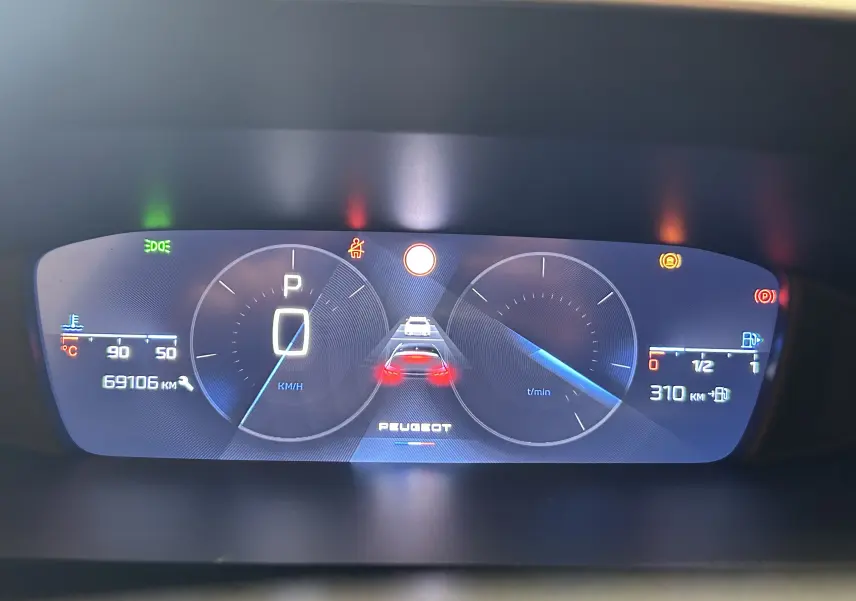 Tableau de bord numérique de Peugeot 308 gris, affichant la vitesse à 0 km/h et une autonomie de 310 km.
