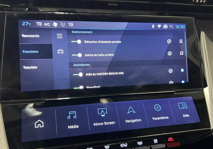 Écran tactile central de la Peugeot 308 gris, affichant les options d'assistance à la conduite et navigation.
