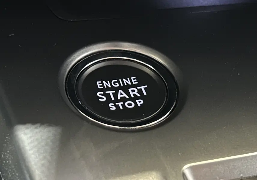 Bouton noir rond "Engine Start Stop" en gros plan sur la console intérieure de la Peugeot 308 gris 2022.
