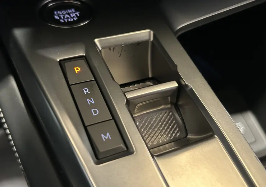 Gros plan sur la console centrale grise de la Peugeot 308 2022, avec les boutons de boîte auto et le bouton start/stop.
