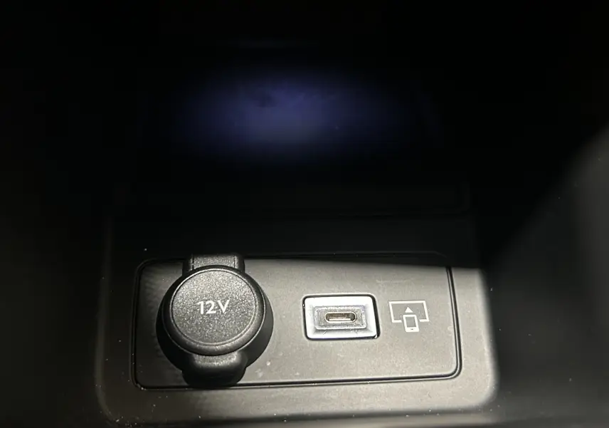 Prise 12V et port USB-C visibles dans la console centrale d’une Peugeot 308 gris 2022, version BlueHDi Allure Pack.