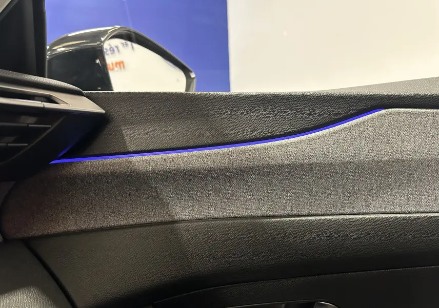 Détail intérieur côté conducteur de la Peugeot 308 gris, avec éclairage d'ambiance bleu sur la garniture de porte.