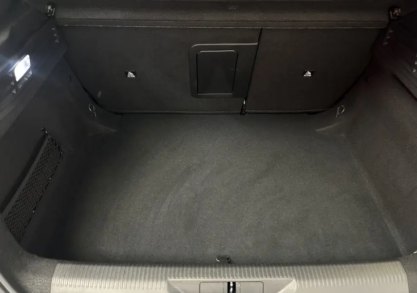 Vue intérieure du coffre spacieux et propre de la Peugeot 308 gris, avec éclairage et filet de rangement latéral.