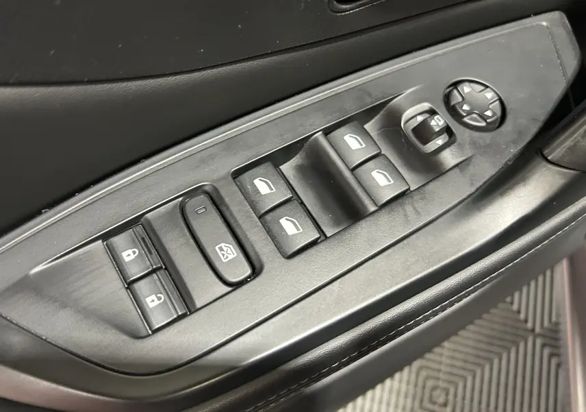 Gros plan sur les commandes de lève-vitres et rétroviseurs côté conducteur d’une Peugeot 308 gris, intérieur noir.