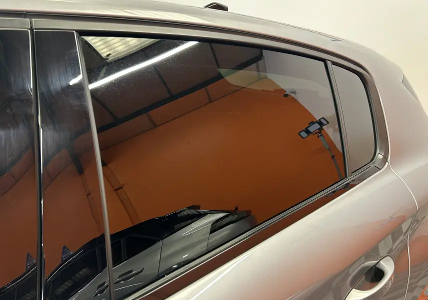 Vue latérale droite sur la porte arrière d’une Peugeot 308 gris métallisé avec vitre teintée et poignée intégrée.