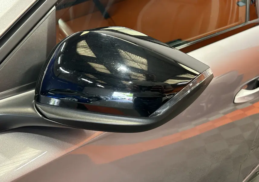 Rétroviseur noir en gros plan côté gauche d'une Peugeot 308 gris métallisé, avec clignotant intégré.