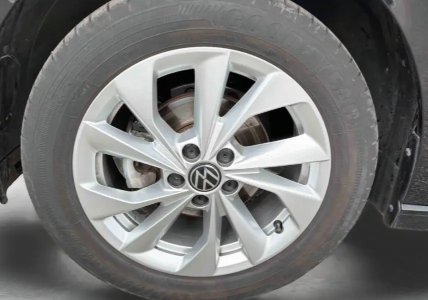 Gros plan sur la jante alliage 16'' Palermo argentée avec logo Volkswagen, montée sur pneu Goodyear d'une Polo noire.