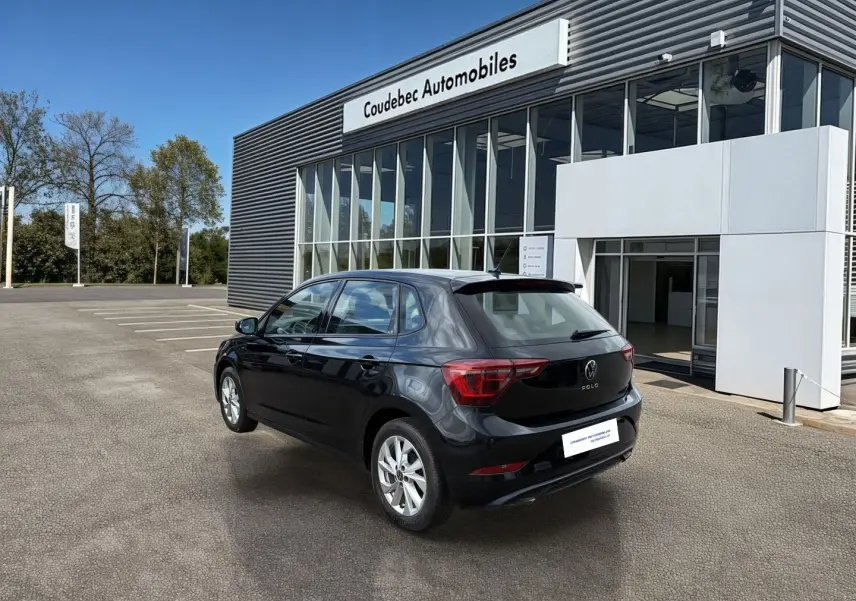 Volkswagen Polo noire vue 3/4 arrière droit, avec jantes alliage 16'' devant un bâtiment moderne.