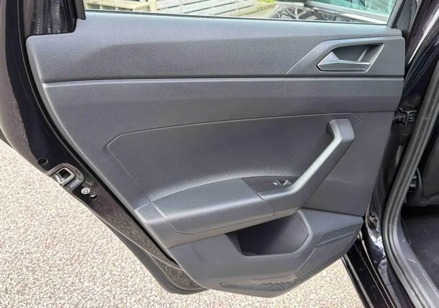 Vue intérieure de la porte arrière gauche noire d’une Volkswagen Polo 2025 avec poignée et commande de vitre.