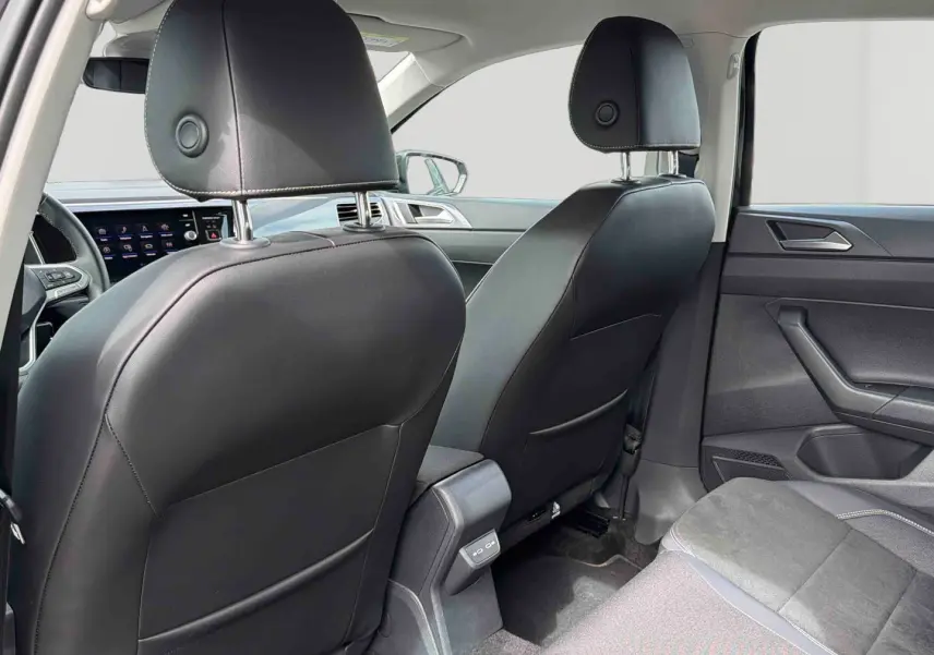 Vue arrière intérieure de la Volkswagen Polo 2025 noire, montrant les sièges avant en cuir et la console centrale.