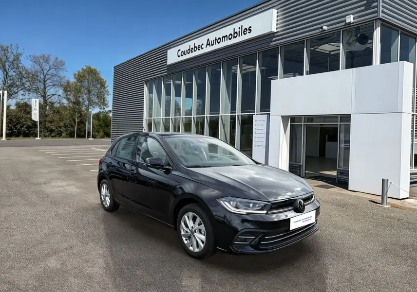 Volkswagen Polo noire vue en 3/4 avant droit devant un bâtiment moderne de concession automobile.