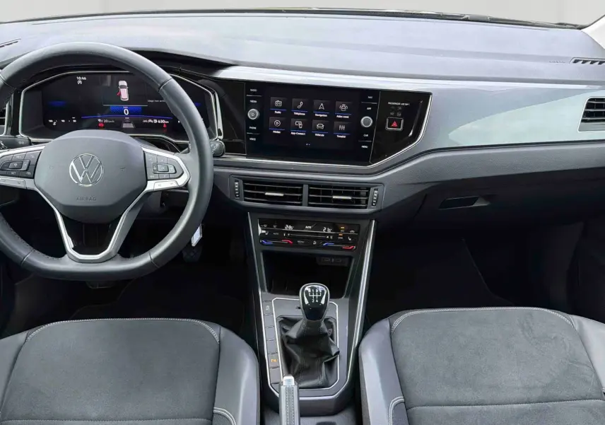 Vue intérieure avant de la Volkswagen Polo noire 2025, montrant le volant cuir multifonctions et la console centrale avec boîte manuelle.