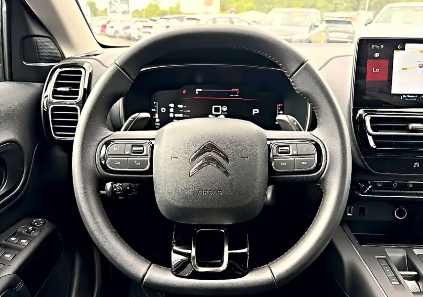 Vue centrée sur le volant cuir noir et le tableau de bord numérique du Citroën C5 Aircross 2025, intérieur moderne.