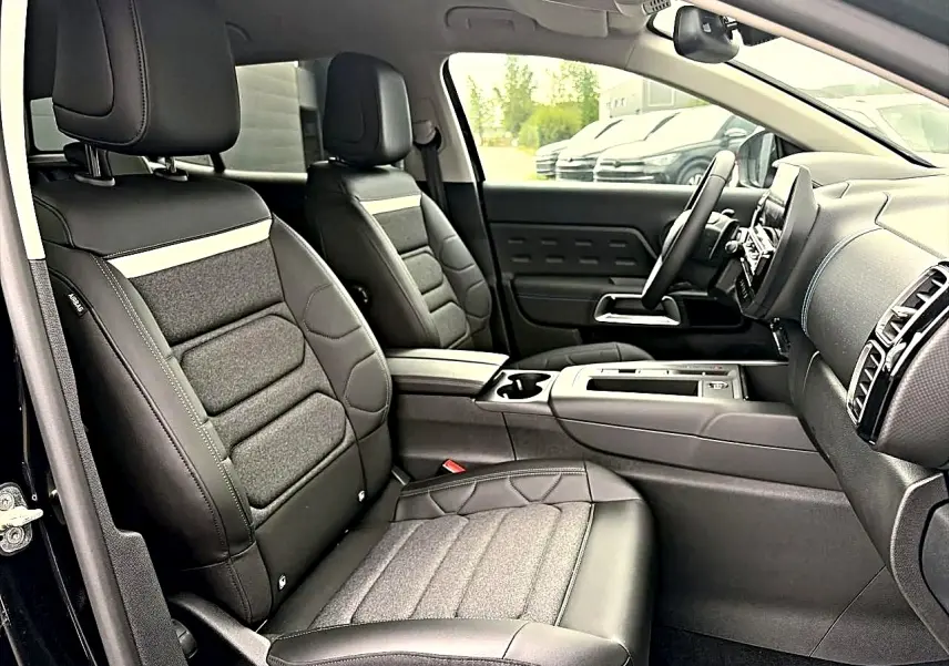 Vue intérieure côté conducteur du Citroën C5 Aircross 2025 noir, sièges cuir et tissu avec console centrale et tableau de bord moderne.