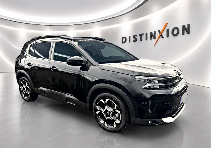 Citroën C5 Aircross noir vue 3/4 avant droit avec jantes alliage et barres de toit en showroom lumineux.