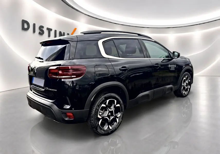 Vue 3/4 arrière droite du Citroën C5 Aircross noir avec barres de toit et jantes alu distinctives.
