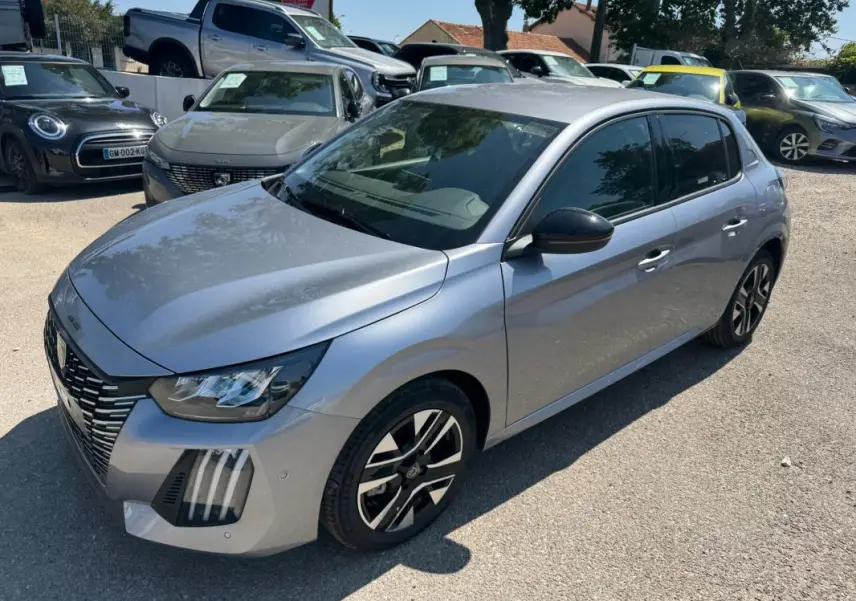 Peugeot 208 Hybrid gris vue 3/4 avant droit, avec jantes alliage noires et calandre distinctive.