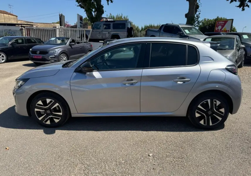 Profil droit d'une Peugeot 208 Hybrid 110 gris 2025 avec jantes alliage 16 pouces et antenne requin.
