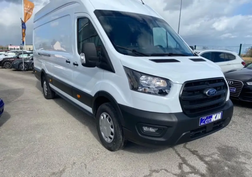 Ford Transit Fourgon blanc vu en 3/4 avant droit, avec calandre noire et pare-chocs noir mat, stationné en extérieur.