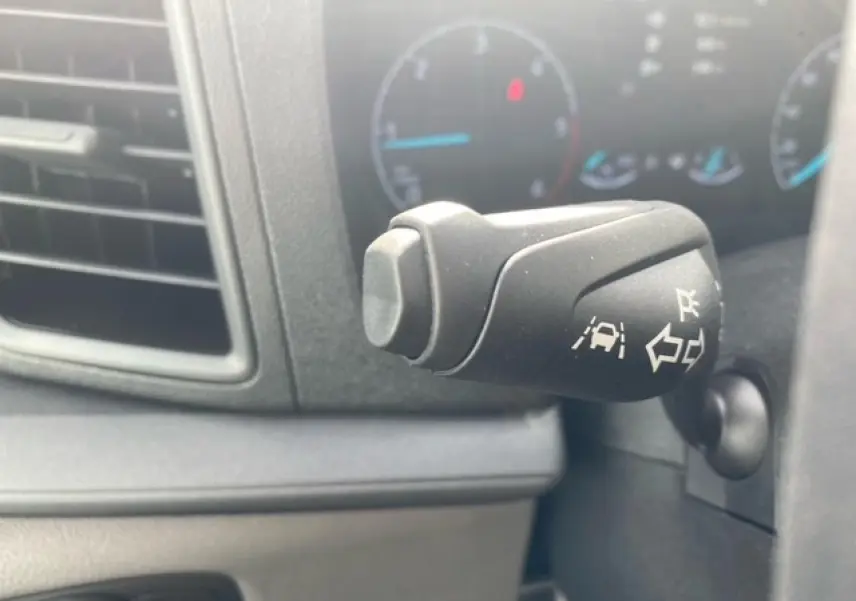 Gros plan sur la commande de clignotant avec assistance au maintien de voie dans l'habitacle du Ford Transit Fourgon blanc.