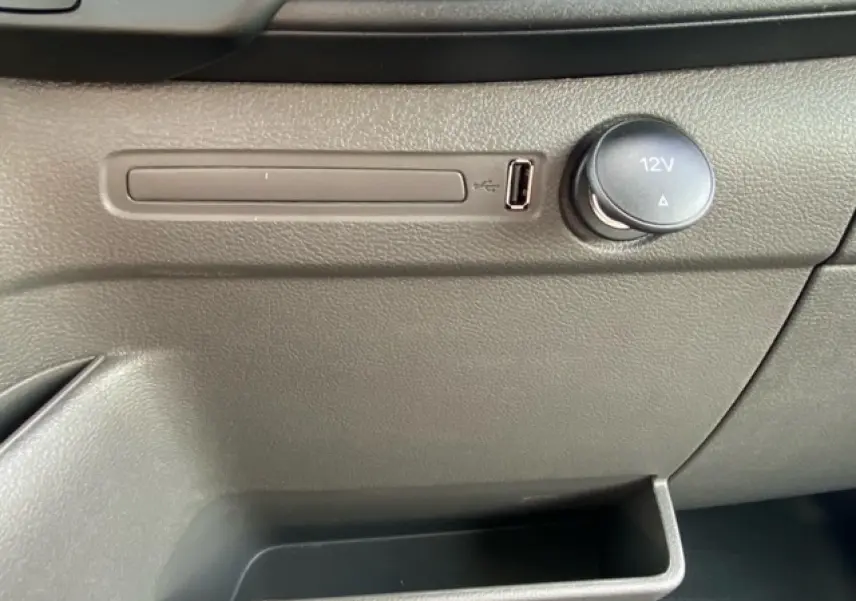Prise USB et allume-cigare 12V en gros plan sur la console intérieure grise du Ford Transit Fourgon blanc 2023.