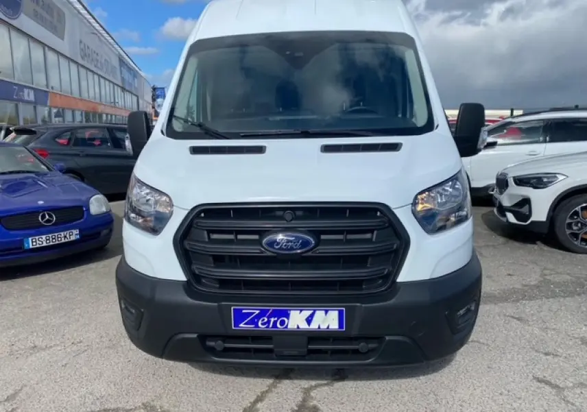 Vue frontale d'un Ford Transit Fourgon blanc 2023 avec calandre noire et plaque "Zéro KM" visible.