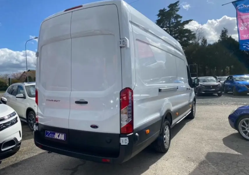 Vue 3/4 arrière droite d'un fourgon Ford Transit blanc 2023 avec porte latérale coulissante et feux arrière verticaux.