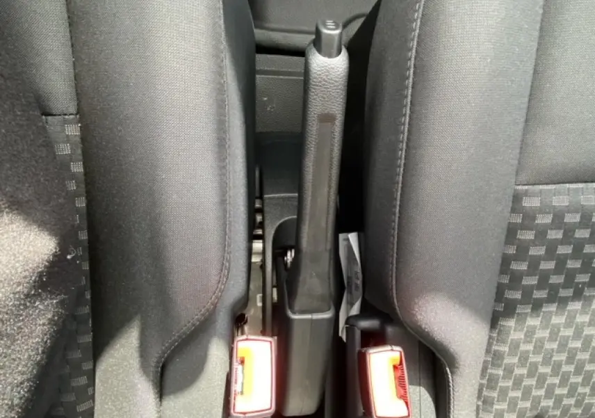 Vue rapprochée du frein à main et des ceintures de sécurité entre les sièges avant du Ford Transit Fourgon blanc 2023.