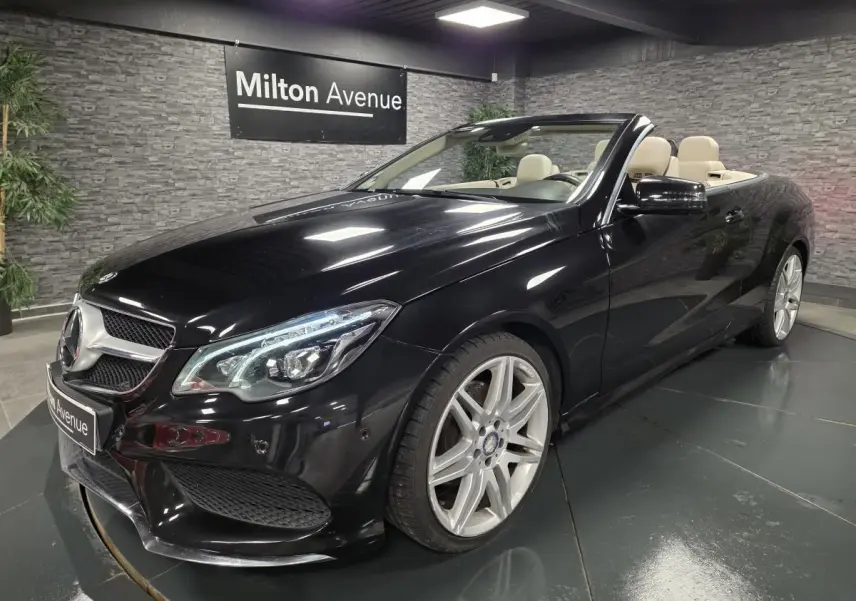 Mercedes Classe E Cabriolet noir en 3/4 avant droit, jantes alliage argent et intérieur beige visible sans capote.
