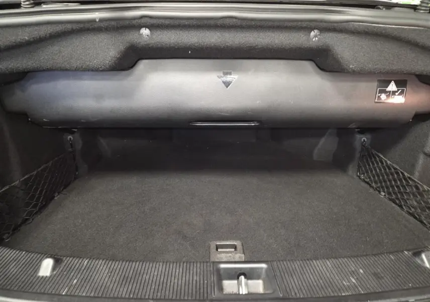 Coffre ouvert noir de la Mercedes Classe E Cabriolet E 250 CDI Fascination, montrant l'espace de rangement vide et les filets latéraux.