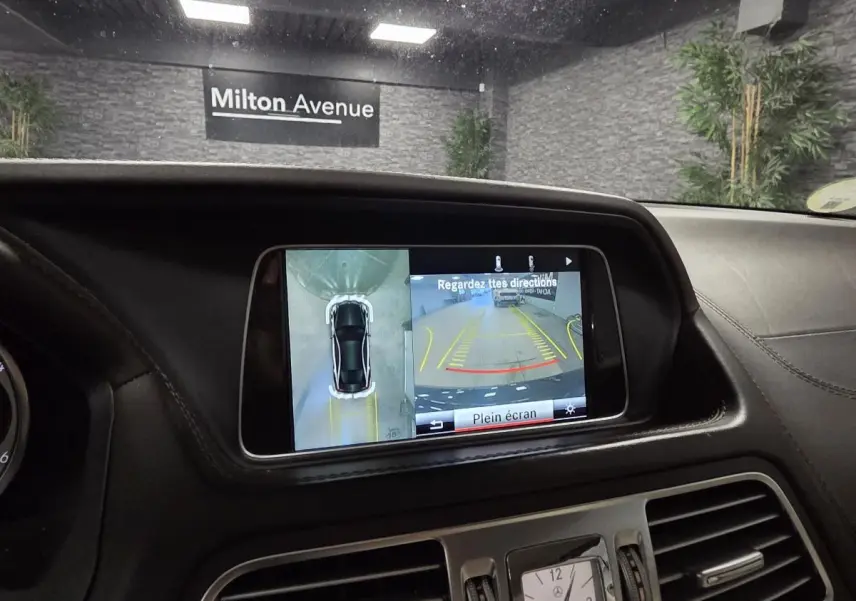 Vue intérieure du tableau de bord d'une Mercedes Classe E Cabriolet noire, écran multimédia affichant la caméra 360° en marche.