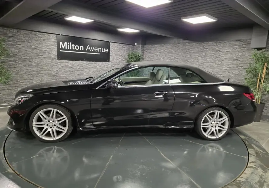 Profil côté gauche d'un cabriolet Mercedes Classe E noir avec jantes alliage 19 pouces dans un showroom.