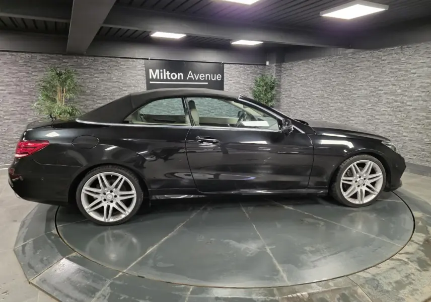 Mercedes Classe E Cabriolet noir vue de profil côté gauche avec capote fermée et jantes alliage visibles.