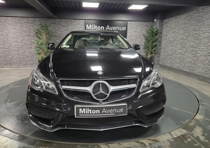 Vue frontale d'un cabriolet Mercedes Classe E noir, avec calandre chromée et logo étoile bien visible.