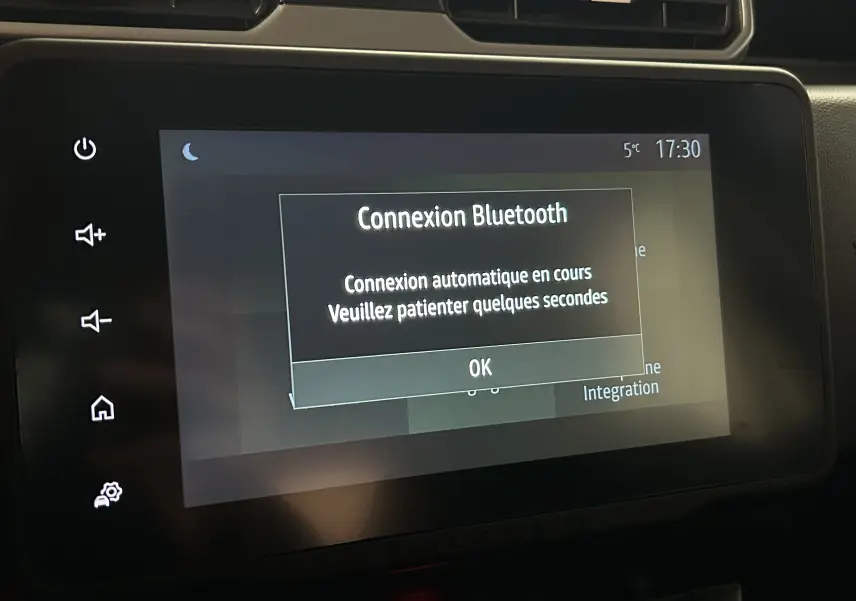 Écran tactile central du Dacia Duster 2024 affichant une connexion Bluetooth en cours, avec boutons tactiles latéraux visibles.