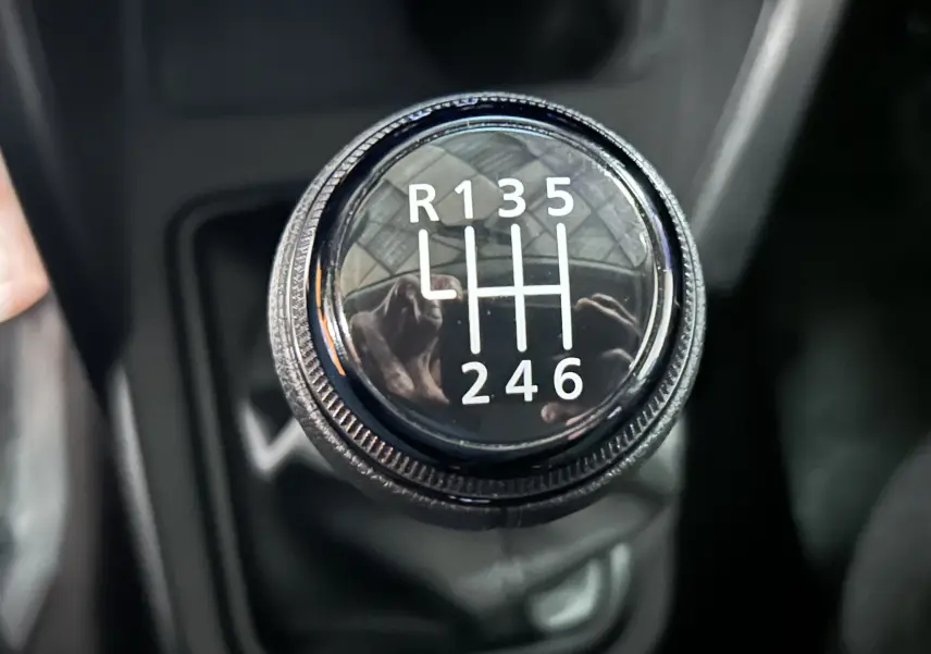 Gros plan sur le levier de vitesses manuel du Dacia Duster 2024, montrant les six rapports et la marche arrière.