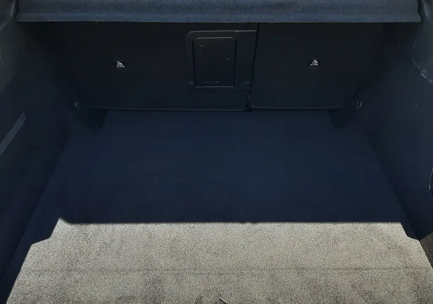 Vue intérieure du coffre spacieux de la Peugeot 408 Hybrid 145ch gris Selenium, avec banquette arrière et cache-bagages visibles.
