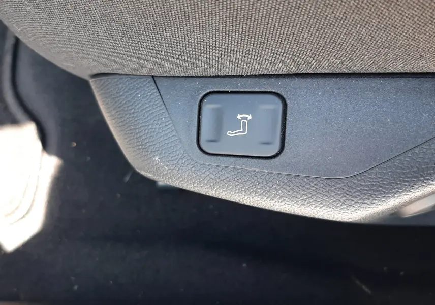 Gros plan sur le bouton de réglage électrique de l'inclinaison du siège côté conducteur dans un Peugeot 408 gris.