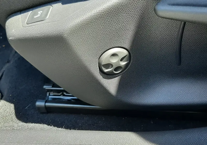 Détail du réglage manuel du siège avant en plastique noir dans l'habitacle d'une Peugeot 408 gris selenium 2024.