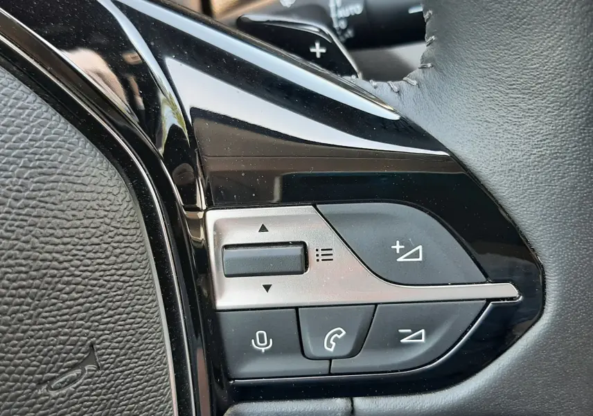 Gros plan sur les commandes du volant côté gauche du Peugeot 408 gris, avec boutons de volume et téléphone.